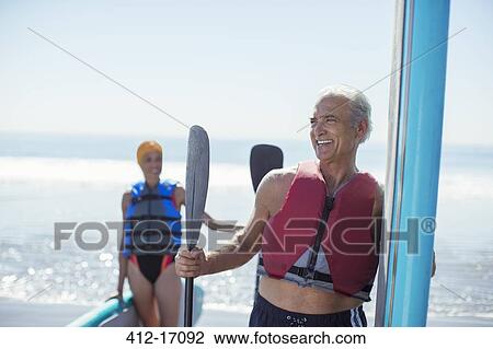 Senior couple with paddleboards on beach View Large Photo Image Stock Image - Senior couple with paddleboards on beach. Fotosearch