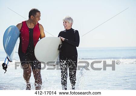 Picture - Senior couple with surfboards on beach. Fotosearch