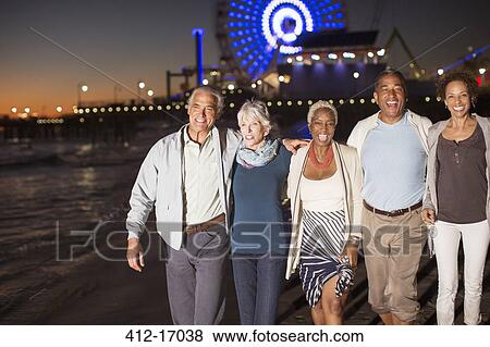 Senior friends walking on beach at night View Large Photo Image Stock Photo - Senior friends walking on beach at night. Fotosearch