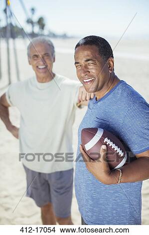 Picture - Senior men with football on beach. Fotosearch