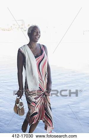 Stock Image - Woman in dress wading in ocean. Fotosearch