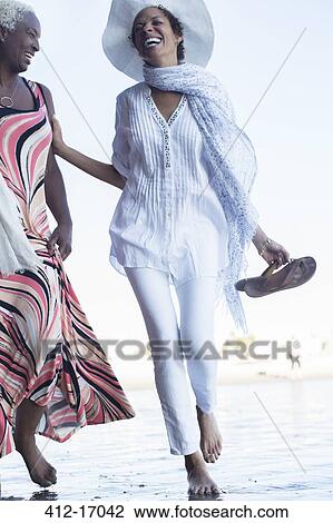 Stock Image - Women walking on beach. Fotosearch