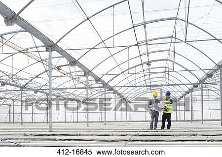 Architect and engineer reviewing blueprint in empty greenhouse View Large Photo Image Stock Photography - Architect and engineer reviewing blueprint in empty greenhouse. Fotosearch