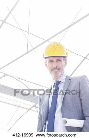 Stock Photo - Portrait of confident architect wearing hard-hat in greenhouse. Fotosearch