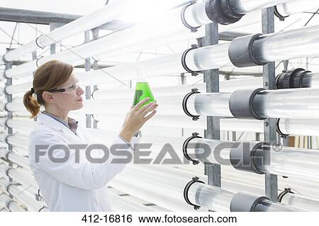 Stock Photograph - Scientist with beaker in greenhouse. Fotosearch