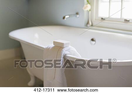 Stock Image - Bar soap and towel on ledge of claw foot tub. Fotosearch