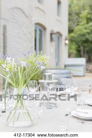 Picture - Bouquet on sunny patio table with place settings. Fotosearch
