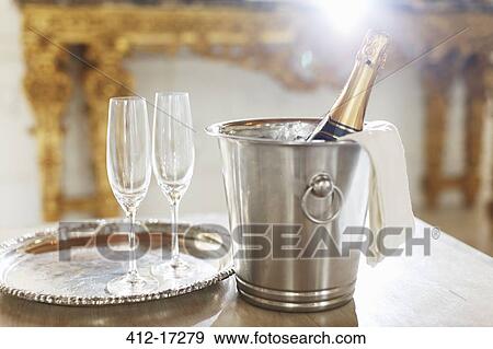 Stock Photo - Champagne in silver bucket next to champagne flutes. Fotosearch
