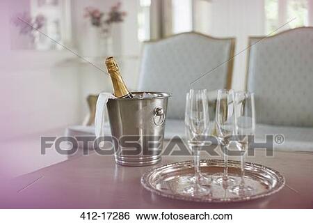 Stock Photograph - Champagne in silver bucket next to champagne flutes. Fotosearch