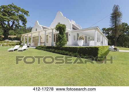 Stock Photo - Hedges and grass surrounding luxury house. Fotosearch