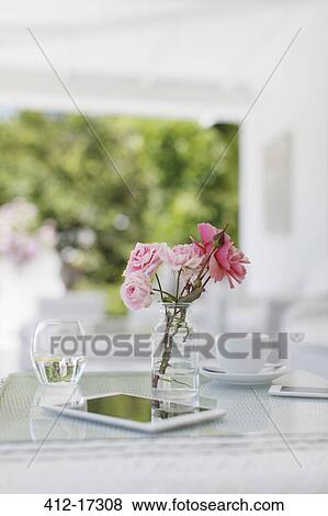 Pink roses on patio table next to coffee cup and digital tablet View Large Photo Image Stock Photo - Pink roses on patio table next to coffee cup and digital tablet. Fotosearch