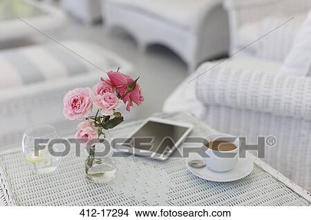 Picture - Pink roses on patio table with coffee cup and digital tablet. Fotosearch
