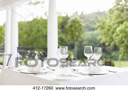 Stock Image - Place settings on patio table. Fotosearch