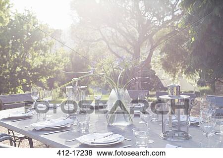 Stock Photo - Place settings on sunny patio table. Fotosearch