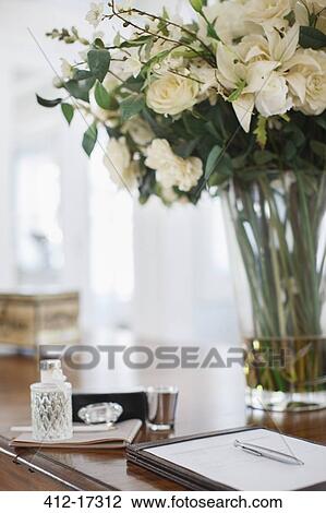 Stock Image - Rose bouquet and notepad on luxury desk. Fotosearch