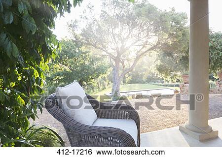 Wicker armchair on tranquil patio View Large Photo Image Stock Photograph - Wicker armchair on tranquil patio. Fotosearch