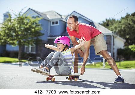 Father pushing daughter on skateboard View Large Photo Image Stock Photo - Father pushing daughter on skateboard. Fotosearch