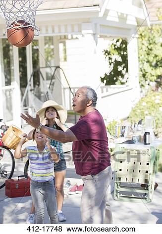 Stock Photo - Grandfather and granddaughters playing basketball. Fotosearch