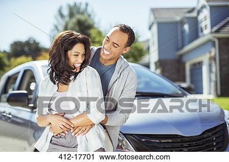 Stock Image - Happy couple hugging in driveway. Fotosearch
