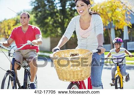 Happy family riding bikes on sunny street View Large Photo Image Stock Photography - Happy family riding bikes on sunny street. Fotosearch