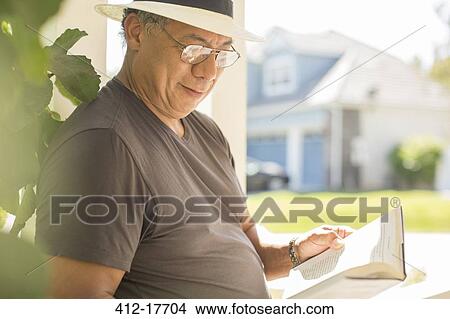 Man reading book on sunny patio View Large Photo Image Picture - Man reading book on sunny patio. Fotosearch