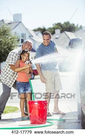 Stock Photo - Multi-generation family washing car in driveway. Fotosearch