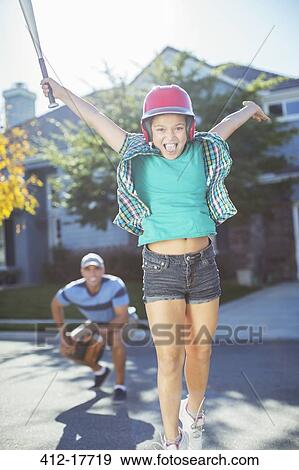 Portrait of cheering girl playing baseball in street View Large Photo Image Stock Photo - Portrait of cheering girl playing baseball in street. Fotosearch