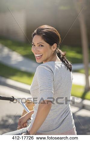 Stock Photograph - Portrait of enthusiastic woman on bicycle. Fotosearch