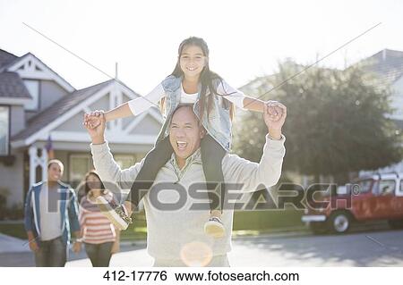 Stock Photograph - Portrait of grandfather carrying granddaughter on shoulders. Fotosearch
