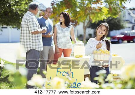 Stock Photo - Portrait of smiling girl holding lemons at lemonade stand. Fotosearch
