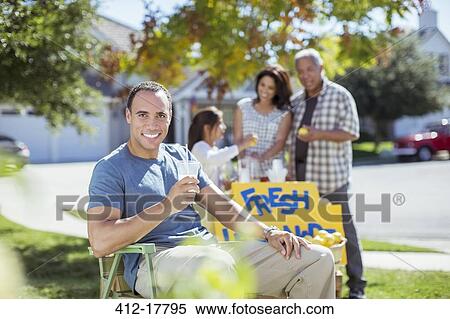 Stock Photography - Portrait of smiling man drinking lemonade at lemonade stand. Fotosearch