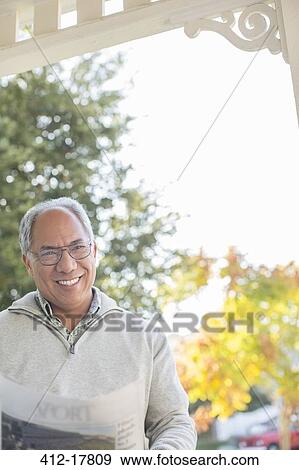 Portrait of smiling man reading newspaper on porch View Large Photo Image Stock Photo - Portrait of smiling man reading newspaper on porch. Fotosearch