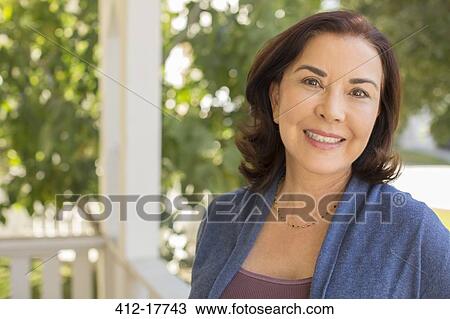 Stock Image - Portrait of smiling woman on porch. Fotosearch