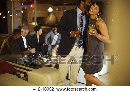 Stock Image - Couple kissing at party. Fotosearch