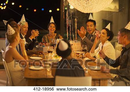 Stock Photograph - Friends cheering at birthday party. Fotosearch