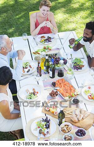 Stock Photo - Friends eating together outdoors. Fotosearch