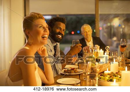 Stock Photograph - Friends laughing at dinner party. Fotosearch