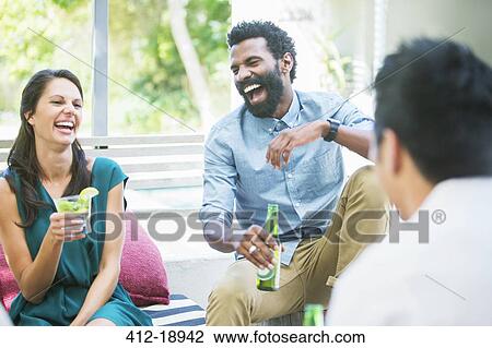 Friends laughing together at party View Large Photo Image Stock Image - Friends laughing together at party. Fotosearch