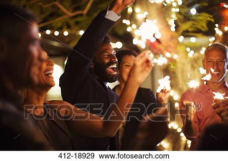 Stock Photo - Friends playing with sparklers at party. Fotosearch