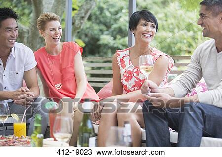 Friends relaxing together at party View Large Photo Image Stock Image - Friends relaxing together at party. Fotosearch