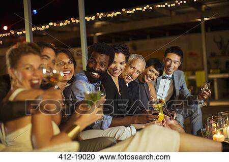 Friends smiling together at party View Large Photo Image Stock Image - Friends smiling together at party. Fotosearch