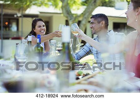 Friends toasting each other at dinner outdoors View Large Photo Image Picture - Friends toasting each other at dinner outdoors. Fotosearch