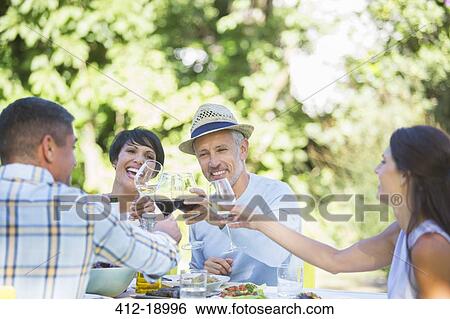 Friends toasting each other at table outdoors View Large Photo Image Stock Photograph - Friends toasting each other at table outdoors. Fotosearch