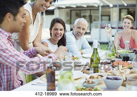 Stock Photo - Woman serving friends at party. Fotosearch