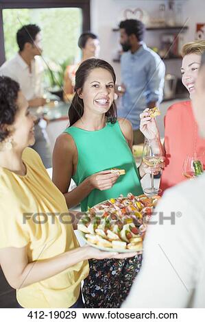Stock Photo - Woman serving friends at party. Fotosearch