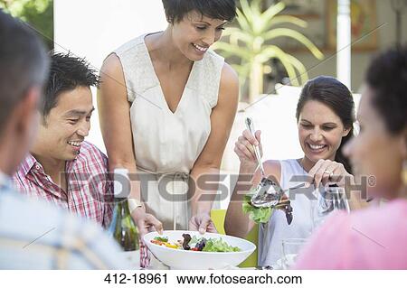 Woman serving friends at table outdoors View Large Photo Image Stock Image - Woman serving friends at table outdoors. Fotosearch