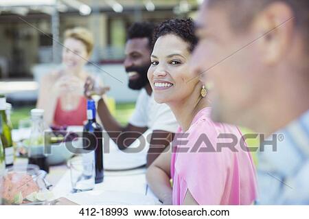 Stock Image - Woman smiling at table outdoors. Fotosearch