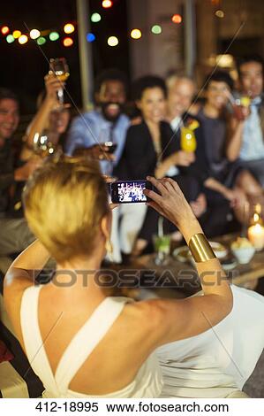 Woman taking picture of friends at party View Large Photo Image Stock Photography - Woman taking picture of friends at party. Fotosearch