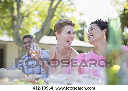 Picture - Women talking at table outdoors. Fotosearch