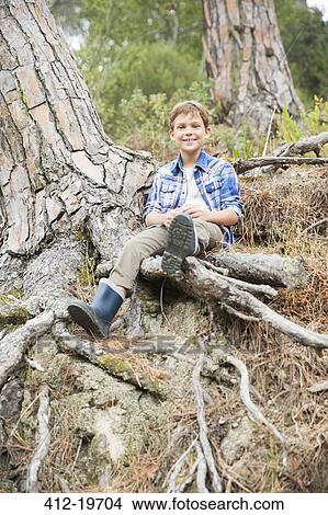 Boy sitting on tree roots in forest View Large Photo Image Picture - Boy sitting on tree roots in forest. Fotosearch